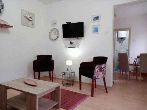 Una sala de estar con sillas, una mesa y un televisor. en Old marine house, en Tivat