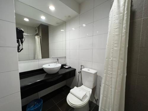 a bathroom with a toilet and a sink and a mirror at SSL Traders Hotel in Taiping