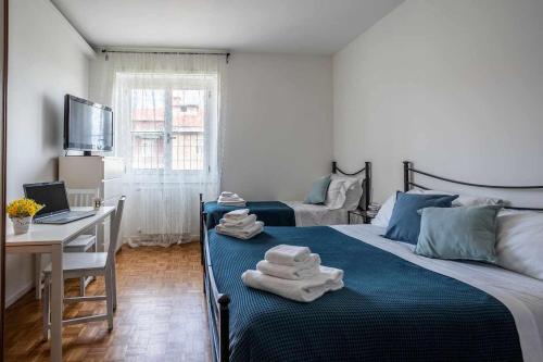 米蘭的住宿－Milano City Apartments - Parking and Comfort - Spacious Apt up to 8 Pax，一间卧室配有两张床和一张带笔记本电脑的书桌
