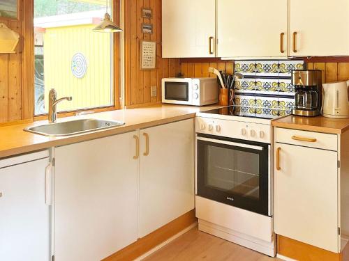 een keuken met witte kasten, een wastafel en een magnetron bij 5 person holiday home in R dby in Rødby