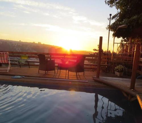 a table and chairs on a deck with the sunset at Posada Verde Natura in Viña del Mar