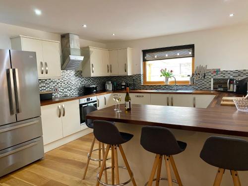 een keuken met witte kasten en een houten aanrecht bij Teaghlach, Cairngorms - Escape Cottages Scotland in Newtonmore