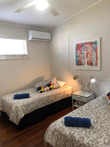 a room with two beds and a table with a lamp at Redland BayBreeze in Redland Bay