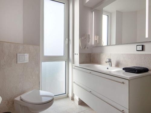 ein Badezimmer mit Toilette, Waschbecken und Spiegel in der Unterkunft 6 Personen Ferienhaus in Wendtorf in Wendtorf