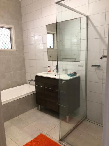 a bathroom with a shower and a sink and a mirror at Redland BayBreeze in Redland Bay