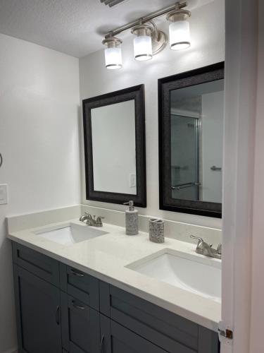 un baño con dos lavabos y dos espejos en Fabulous Apartment 8 pax close Disney, en Kissimmee