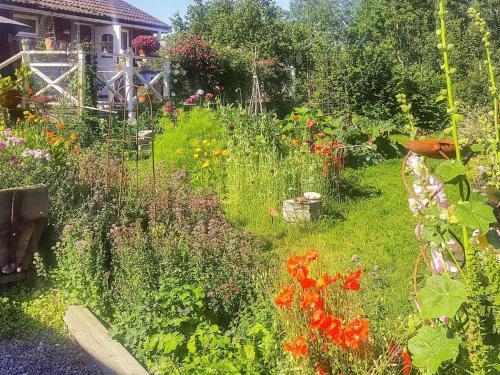 un jardin avec des fleurs colorées et une maison dans l'établissement 5 person holiday home in FLEN, à Flen