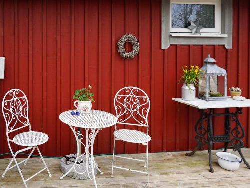 un patio con 2 sedie, un tavolo e una parete rossa di 5 person holiday home in FLEN a Flen