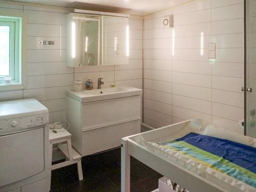 ein weißes Bad mit einem Waschbecken und einem Kinderbett in der Unterkunft Holiday home öSTHAMMAR II in Östhammar