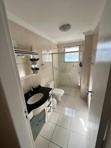 a white bathroom with a sink and a toilet at Apartamento pé na areia Balneário Camboriú! Av. Atlântica. in Balneário Camboriú