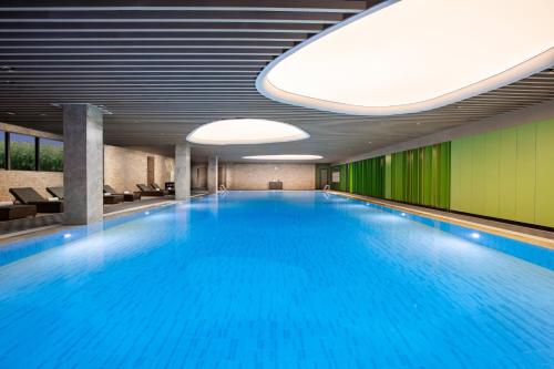 uma grande piscina com água azul num edifício em Holiday Inn Resort Guiyang Qingyan, an IHG Hotel em Guiyang