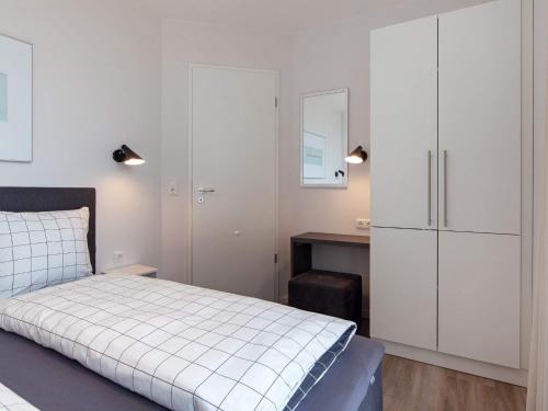 Schlafzimmer mit einem Bett, weißen Schränken und einem Schreibtisch in der Unterkunft Apartment Wendtorf X in Wendtorf