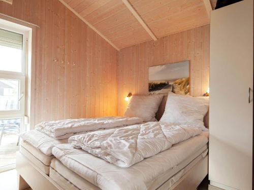 1 cama blanca grande en una habitación con paredes de madera. en Two-Bedroom Holiday home in Grömitz 2, en Grömitz