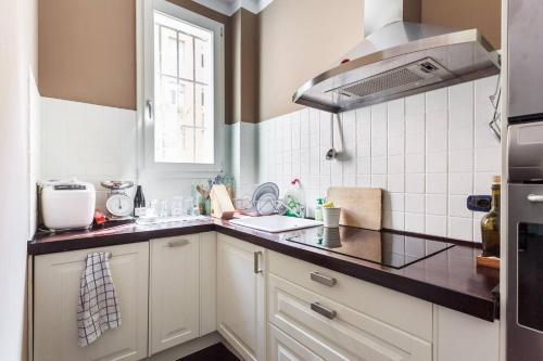 Una cocina con gabinetes blancos y una encimera negra. en Casa di Gino, en Bolonia