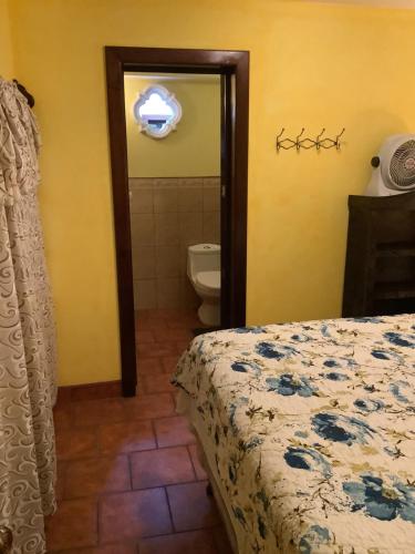 a bedroom with a bed and a bathroom with a toilet at La casita de Angie in Antigua Guatemala