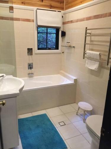 a bathroom with a tub and a sink and a toilet at Holly Lodge in Medlow Bath