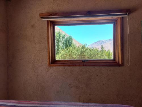 a window in a room with a mountain view at Piuquenes Lodge - Cabañas, Viñedos y estrellas en Horcón, Valle de Elqui in Horcon