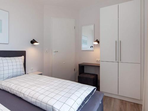a bedroom with a bed and white cabinets and a desk at Exklusive Meerblickwohnung in 1 Reihe in Wendtorf
