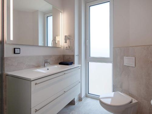 a bathroom with a sink and a toilet and a mirror at Exklusive Meerblickwohnung in 1 Reihe in Wendtorf
