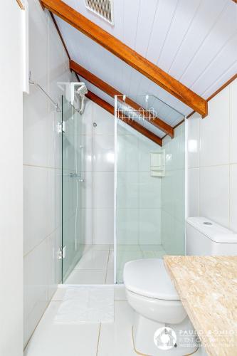 a bathroom with a toilet and a glass shower at Sua Casa em Canela in Canela