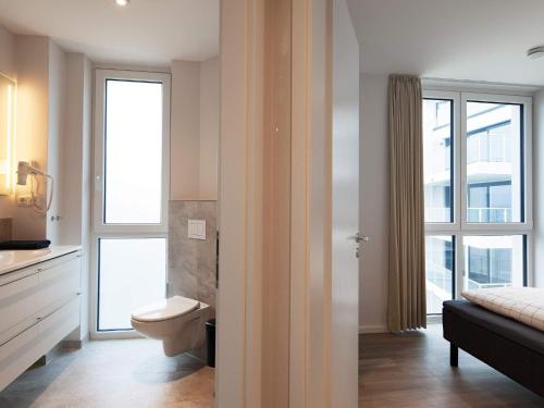 a bathroom with a toilet and two windows at Apartment Wendtorf IX in Wendtorf