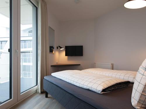 Apartment Wendtorf IX في Wendtorf: غرفة نوم بسرير ونافذة كبيرة