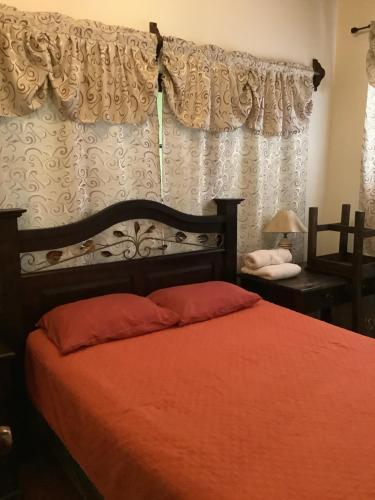 a bedroom with a bed with red sheets and a window at La casita de Angie in Antigua Guatemala