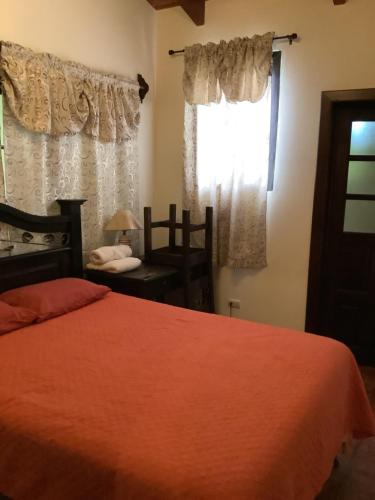 a bedroom with a bed and a window and a chair at La casita de Angie in Antigua Guatemala