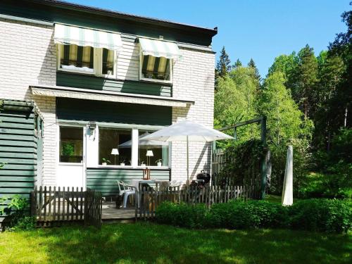 a white house with a table and an umbrella at 6 person holiday home in EKER in Ekerö