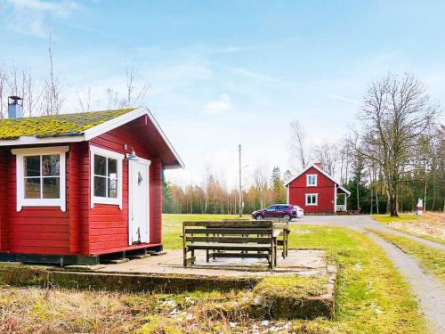 a red cabin with a bench and a red house at 8 person holiday home in LJUNG in Ljung