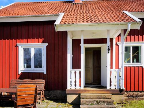 a red house with a white door and a bench at 8 person holiday home in LJUNG in Ljung