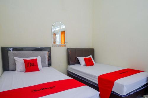 two beds in a room with red and white pillows at RedDoorz Syariah near Universitas Slamet Riyadi Solo in Karanganyar