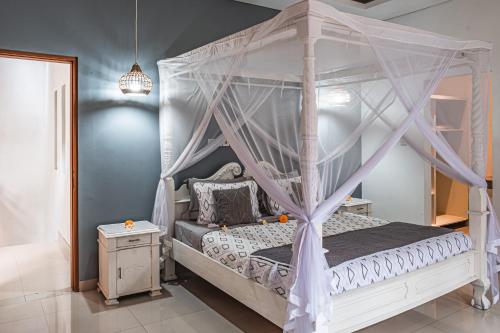 ein Schlafzimmer mit einem weißen Himmelbett und einem Nachttisch in der Unterkunft Villa Mali Legian in Legian