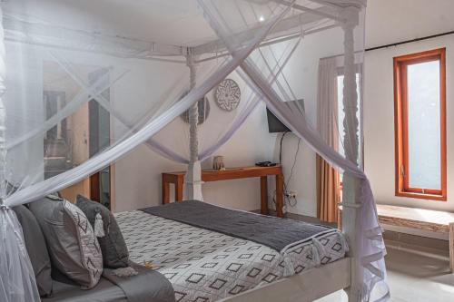 a bedroom with a canopy bed and a window at Villa Mali Legian in Legian