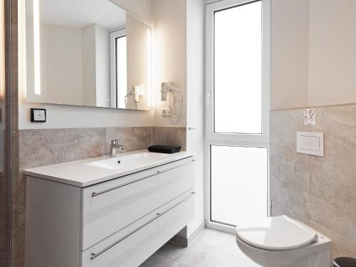 ein weißes Badezimmer mit Waschbecken und Toilette in der Unterkunft 6 Personen Ferienhaus in Wendtorf in Wendtorf