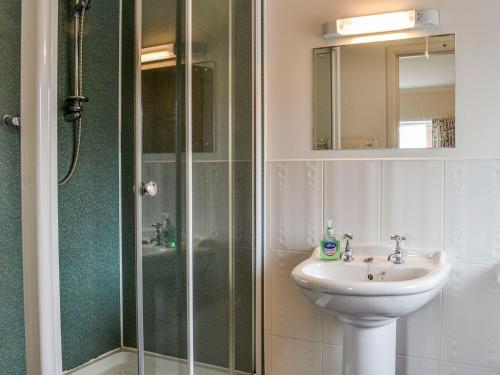 Drummore的住宿－Auld Dairy Cottage，浴室配有盥洗盆、淋浴和盥洗盆。
