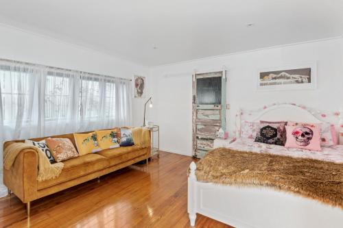 a bedroom with a bed and a couch in it at Waterfront Sunsets Studio in Ngunguru