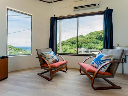 2 sillas en una habitación con ventana grande en 癒楽 伊豆大島 en Oshima
