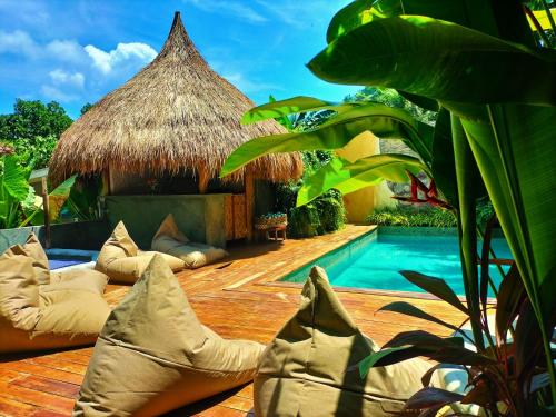 un complexe avec une piscine et un toit de chaume dans l'établissement Terra Sancta Resort, à El Nido