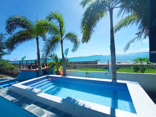 una piscina con palmeras y el océano en The Beach Villa by M, en Manguisoc