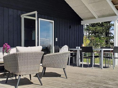 a patio with wicker chairs and a table on a deck at 5 person holiday home in R m in Kongsmark