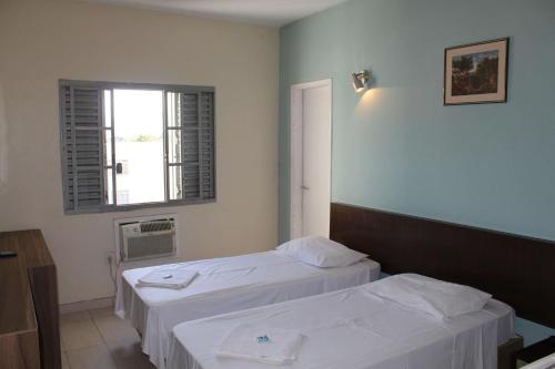 Habitación de hotel con 2 camas y ventana en Espigão Palace Hotel, en Resende