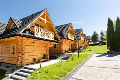 a row of wooden cabins in a row at Osada Chłabówka Zakopane & SPA in Zakopane