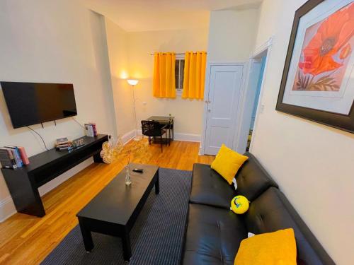 a living room with a black leather couch and a table at Home sweet home in the heart of Wilmington. in Wilmington