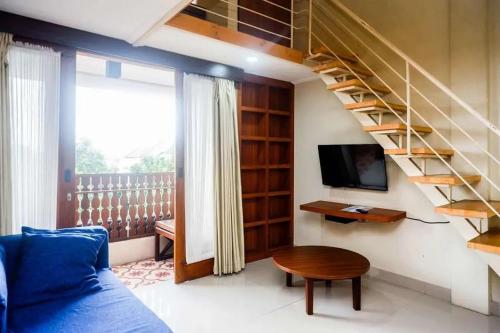 a living room with a staircase and a blue couch at Urbanview Rumah Kandjani Yogyakarta in Yogyakarta
