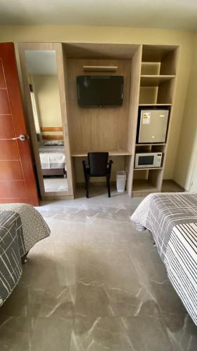 a bedroom with two beds and a flat screen tv at La Posada de Pepe in Piura