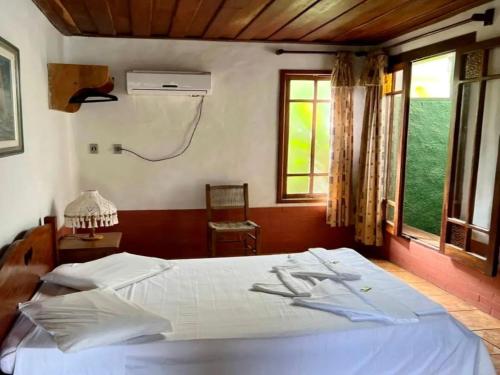 a bedroom with a white bed and a window at Pousada Refugium in Itacaré