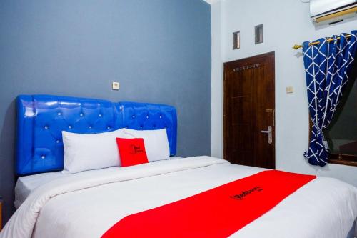 a bed with a blue headboard and a red blanket at RedDoorz at Pakuncen Malioboro Yogyakarta in Yogyakarta