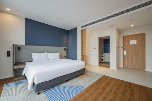 a bedroom with a white bed and a blue wall at Holiday Inn Express Nanning Jiangnan by IHG in Nanning