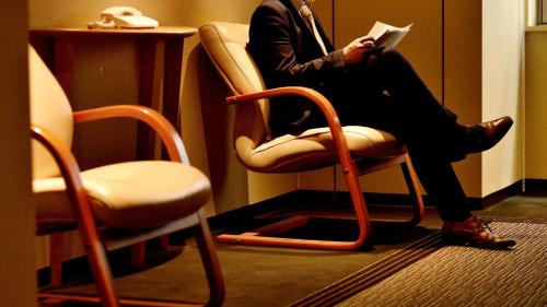 a man sitting in a chair reading a book at ANA Holiday Inn Sendai by IHG in Sendai